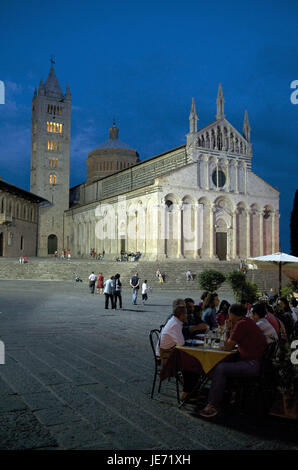 Italy, Tuscany, La Maremma, Massa Marittima, Piazza Garibaldi and cathedral at night, tourists in the street cafe, Stock Photo