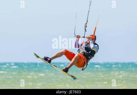 Kitesurfer flying in the air as he does a stunt while at sea on a windy day. Stock Photo