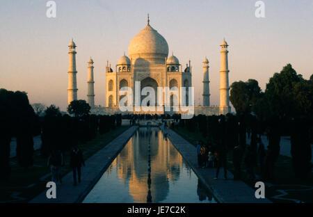 India, Uttar Pradesh, Agra, Taj Mahal in evening light reflected in rippled surface of watercourse through formal gardens in foreground with visitors on each side. Stock Photo