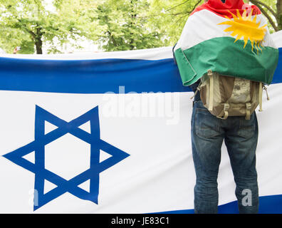 Berlin, Germany. 23rd June, 2017. A pro-Israeli protestor wearing the Kurdish flag stands in front of an Israeli flag during a demonstration against Al-Quds Day in Berlin, Germany, 23 June 2017. Al-Quds Day, which takes its name from the Arabic name of Jerusalem, is an Iranian-sponsored show of solidarity with Palestinians and against Israel. The day is a national holiday in Iran. Demonstrations are held in the US, Canada, the UK, Sweden and Germany as well as the Middle East. Photo: Paul Zinken/dpa/Alamy Live News Stock Photo
