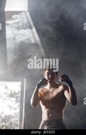 Strong boxer in the rays of the sun and smoke trains in the gym Stock Photo