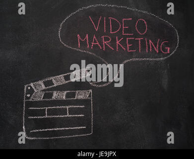Open movie clapper and speech bubble with video marketing writing drawn with chalk on blackboard Stock Photo