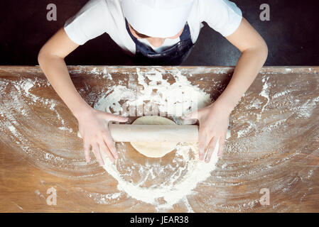 top view of child making pizza dough on wooden tabletop Stock Photo