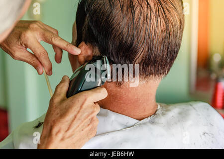 Hair stylist cutting senior asian man's gray hair Stock Photo