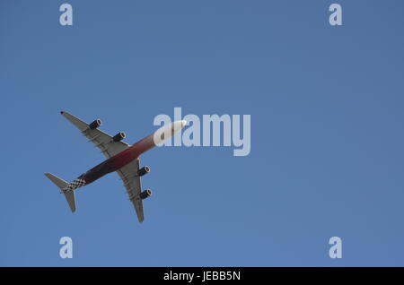 White and Dark Red Four Turbine Aircraft flying Upwards Stock Photo