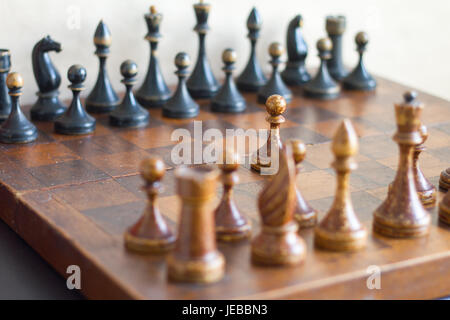 Vintage wooden chess pieces on an old chessboard. Stock Photo