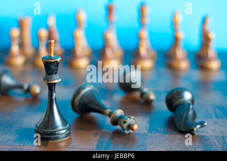 Ancient wooden chess pieces on an old chessboard. On a blue background. Stock Photo