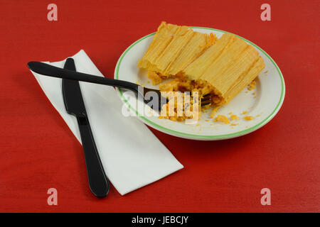 Chicken and jalapeno tamale on plate with napkin and plastic fork and knife Stock Photo