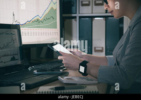 business girl looking for new date about graphic on digital tablet monitor connecting smartwatch while sitting. woman view internet website with pad. Stock Photo