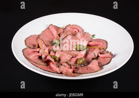 Plate of cold cuts with capers.Cutting meat on a plate with capers Stock Photo