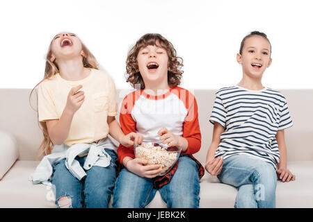 Cheerful group of  friends sitting on couch with popcorn and have fun Stock Photo