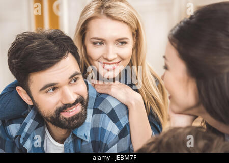 Two young couples lying on floor, having fun and using laptop Stock Photo