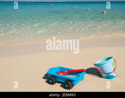 Childrens bucket and spade plastic toys on beach in summer on tropical ocean coast Stock Photo