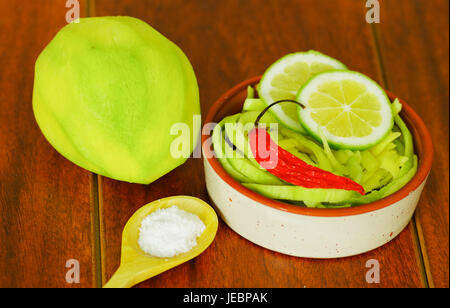 Close up shot of small sliced mango served with salt and a red chilli pepper on a plate Stock Photo