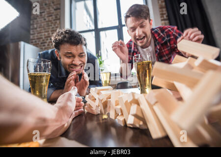 young men playing jenga game, jenga blocks falling. young people having fun concept Stock Photo