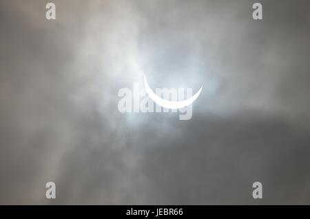 Partial Solar Eclipse seen through clouds Stock Photo