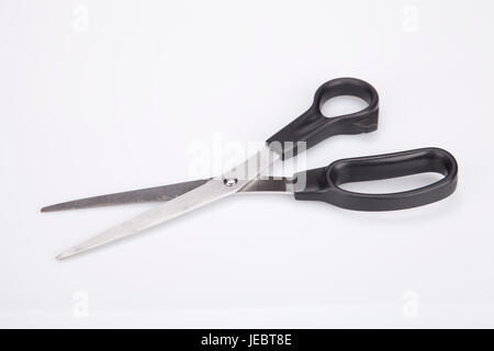 A pair of black scissors on a white surface. Black scissors isolated on white background. Stock Photo