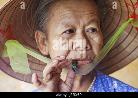 Vietnam, Hoi In, old woman with typical hat smokes cigar, portrait, Stock Photo