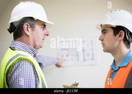 Architect On Site Discussing Plans With Builder Stock Photo