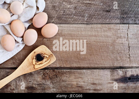 Farm fresh organic brown chicken eggs from free range chickens with an old olive wood antique spatula over a rustic wooden background. Stock Photo