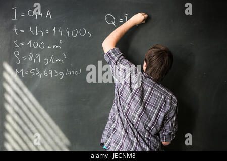 College student solving a math problem during math class in front of the blackboard/chalkboard (color toned image) Stock Photo