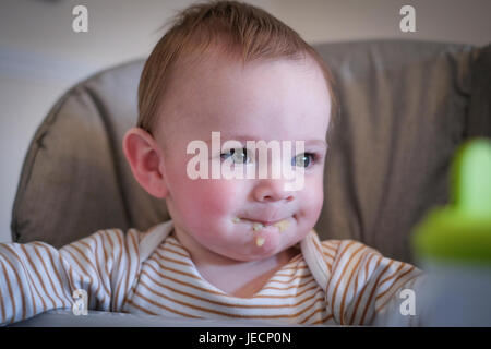 baby boy in high chair with food on face Stock Photo