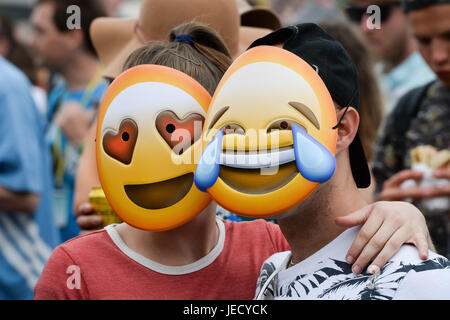 People wear emoji masks in the crowd in front of the Pyramid stage, while the Hacienda Classical Orchestra open the start of the music at the Glastonbury Festival, at Worthy Farm in Somerset. Stock Photo