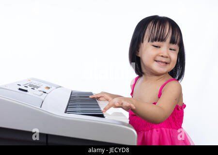 Asian Chinese little girl playing electric piano keyboard in isolated white background. Stock Photo