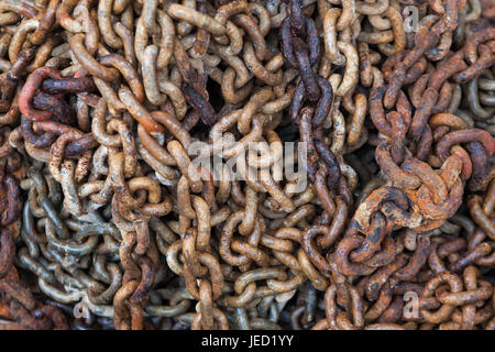 Big rusty marine chain, stacked in a pile on the shore Stock Photo