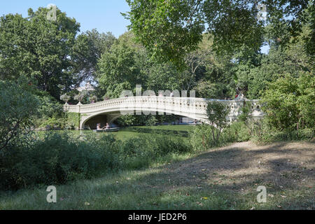 Central Park and white bow bridge with people passing in a sunny day in New York Stock Photo