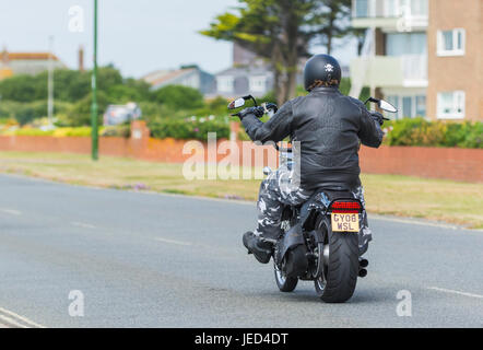Motorcyclist wearing a Harley Davidson jacket riding on a Harley Davidson motorcycle. Harley Davidson bike. Stock Photo