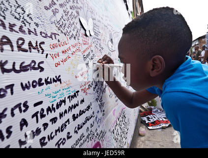 Families and friends writing on the wall of condolence in the aftermath of the fire that destroyed the 24-story Grenfell Tower in North Kensington, London on 14th June 2017.  The death toll officially at 75 but will no doubt rise to three figures. Stock Photo