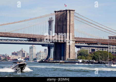 On the water, East River under the Brooklyn Bridge. Speed boat, ferry, jet skis. Stock Photo