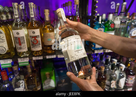 A discerning consumer chooses a bottle of Casamigos ultra-premium tequila in a liquor store in New York on Thursday, June 22, 2017. Diageo has purchased Casamigos, created by actor George Clooney and partners, for approximately $1 billion. Clooney created the tequila company with Rande Gerber and Michael Meldman in 2013. (© Richard B. Levine) Stock Photo