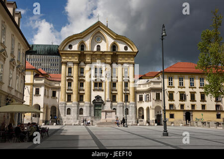 Ursuline Church of the Holy Trinity with marble statues of the Holy Trinity column at Congress Square in Ljubljana Slovenia with dark clouds Stock Photo