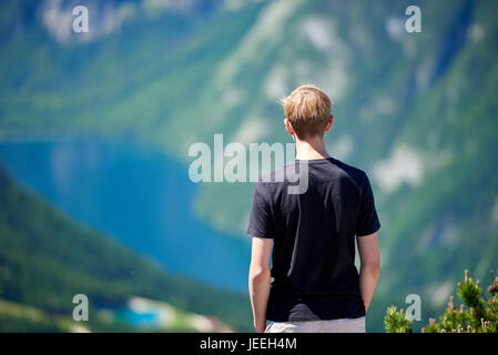Young man standing on a mountain and looking to the valley bellow Stock Photo