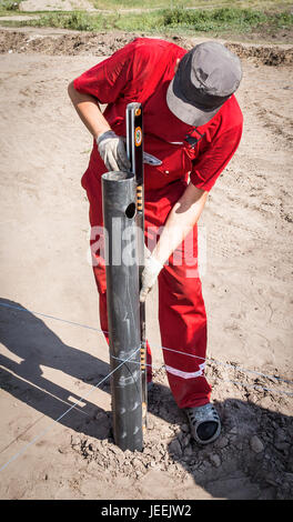 The worker measures the verticality of the pile at a construction site Stock Photo
