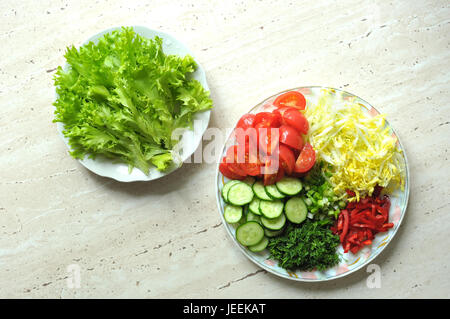 Mix of fresh organic raw sliced vegetables on two white plates on the wooden table. Top view, flat lay. Stock Photo