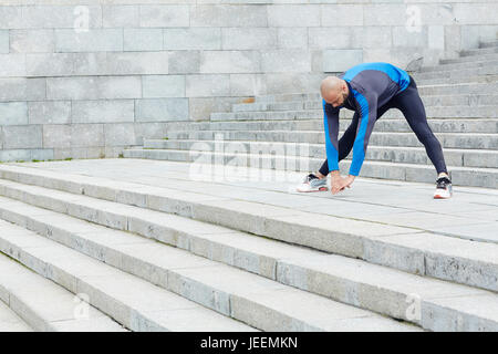 Acrtive young man doing stretching exercise Stock Photo