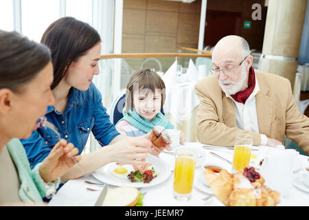 Happy family sitting by table and having breakfast Stock Photo