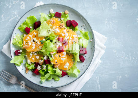 Beetroot salad with oranges, walnuts and feta cheese on blue background with copy space. Healthy homemade vegetarian summer beet salad. Stock Photo