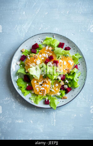 Beetroot salad with oranges, walnuts and feta cheese on blue background with copy space. Healthy homemade vegetarian summer beet salad. Stock Photo
