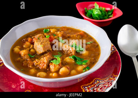 Famous Moroccan soup harira with meat, chickpeas, lentils, tomatoes and spices. Dark photo. Stock Photo