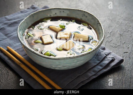 Japanese miso soup in ceramic bowl on black stone table, copy space. Asian miso soup with tofu. Stock Photo