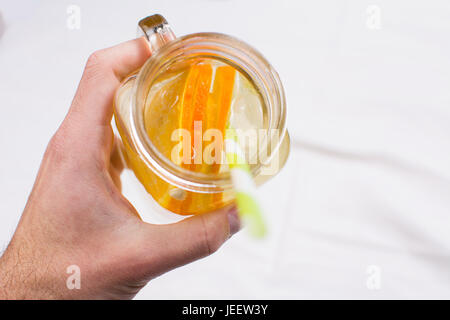 Man drinking water with orange from a glass jar Stock Photo