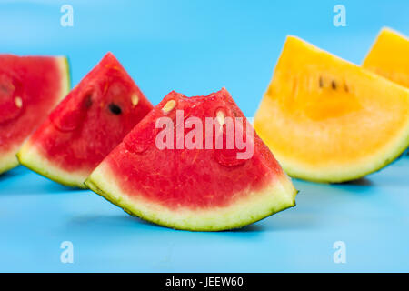 Yellow and red watermelon slices on blue background Stock Photo