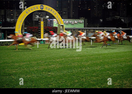 Horizontal view of racehorses crossing the winning post at the Happy Valley racecourse in Hong Kong, China. Stock Photo