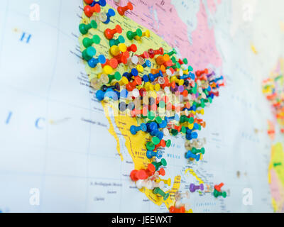 Many colourful pins in a wall map of America. The map is hanging on the wall of a US tourist destination where visiting tourists are asked to mark the Stock Photo