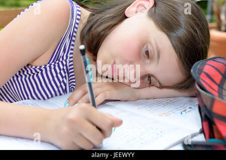 a bored teenage girl is doing her homework Stock Photo