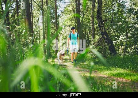 Young man walking with his dog (labrador retriever) in forest. Summer time and vacations theme. Stock Photo